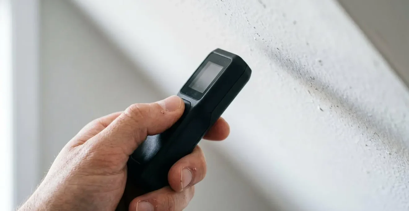 Gros plan sur un mètre laser mesurant la hauteur sous plafond dans une zone de sous-pente