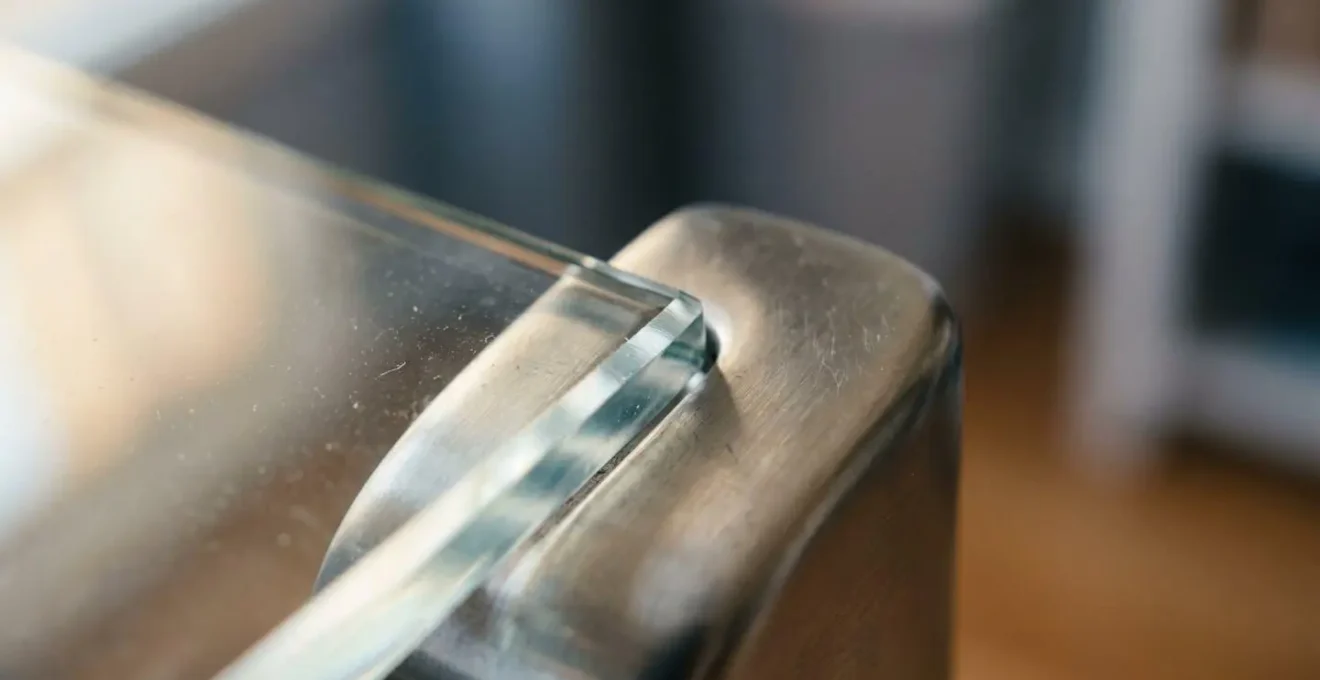 Gros plan sur une jonction architecturale entre verre et métal montrant la texture et les détails de fabrication d'une verrière moderne, avec des reflets naturels et une profondeur de champ réduite